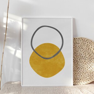 May include: A framed print with a minimalist abstract design featuring a yellow circle with a gray circle overlapping it.