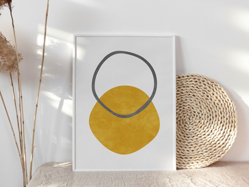 May include: A framed print with a minimalist abstract design featuring a yellow circle with a gray circle overlapping it.