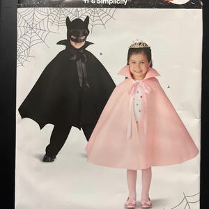 May include: A Simplicity sewing pattern envelope 10109 featuring two costume capes. One is a black cape with a bat-ear mask, and the other is a light pink cape with a high collar and ribbon tie. The packaging includes text reading IT'S SO EASY.