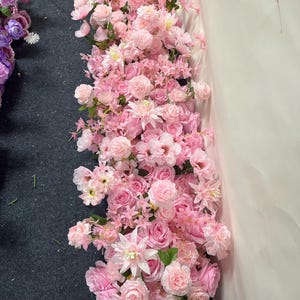 Puede incluir: Un vibrante arreglo de flores artificiales rosas, incluyendo rosas y otras flores, en cascada. Las flores var&iacute;an en tonos de rosa claro a oscuro, con hojas verdes. Adecuado para bodas u otros eventos.
