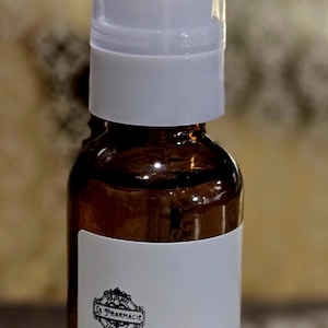 May include: A brown glass bottle with a white pump top and label. The label says "Serum de Sois for Hair Marseille 1 oz / 29mL La Pharmacie d'Invention".