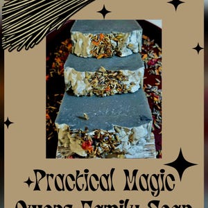 Könnte beinhalten: Drei gestapelte, rechteckige Seifen mit einem dunkelgrauen Farbton, verziert mit getrockneten Kräutern und Blumen. Die Seifen sind mit "Practical Magic Owens Family Soap" beschriftet, mit einer Besen-Grafik im Hintergrund. Das Bild hat einen braunen Hintergrund mit schwarzen Sternakzenten.
