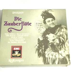 May include: A vintage record album cover featuring a black and white photo of a man in a feathered costume holding a mirror. The album is titled "Die Zauberflöte" by Mozart. The album cover also includes the names of the performers, including Tiana Lemnitz, Helge Rosvaenge, Erna Berger, Gerhard Hüsch, Wilhelm Strienz, Favres Solistien Vereinigung, Berliner Philharmoniker, and Sir Thomas Beecham.