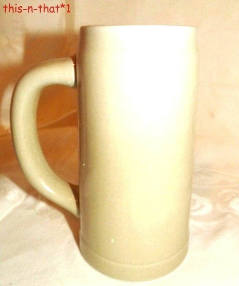 Puede incluir: Un jarro de cerveza de cer&aacute;mica beige claro sin decoraci&oacute;n, con asa. El jarro est&aacute; vac&iacute;o.