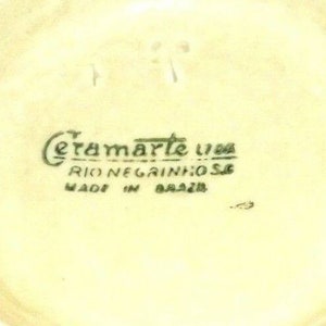 Puede incluir: Primer plano de la parte inferior de un objeto de cer&aacute;mica con el texto "Ceramarte Lda Rio Negrinhos Made in Brazil" en letras verdes.
