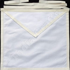 May include: A white apron with cream-colored trim and ties. The apron features a triangular bib and a rectangular body. The edges are neatly finished with a cream-colored border, and the ties are made of the same material.