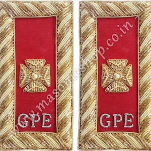 Puede incluir: Par de charreteras rojas con ribete dorado y crema. Cada charretera presenta un diseño de cruz dorada con un centro de perla y las letras "GPE" en plata. Probablemente para un uniforme o atuendo ceremonial.