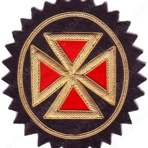Puede incluir: Un emblema bordado en negro y dorado con un diseño de cruz roja en el centro. El emblema tiene un borde dorado y un borde exterior dentado en forma de estrella. La cruz está formada por cuatro triángulos rojos.