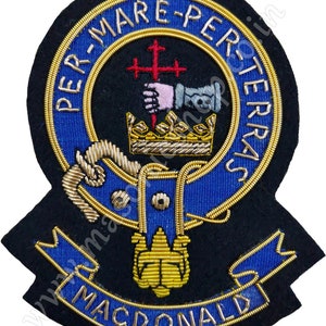 May include: A black and blue embroidered patch with gold trim. The patch features a crown, a hand holding a cross, and the text "PER-MARE-PER-TERRAS" around the top. The text "MACDONALD" is on a blue ribbon at the bottom.