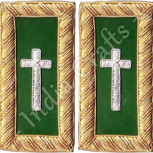 May include: Two rectangular green patches with a white cross design. The patches are framed with gold-colored, intricately woven trim. The text "Indi" and "afts" are partially visible on the patches.