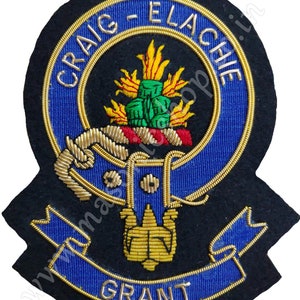 Puede incluir: Un parche bordado de fieltro negro con un escudo azul y dorado. El escudo presenta una cuerda dorada, una corona verde y dorada y una cinta roja y dorada. El texto "CRAIG - ELACHIE" está escrito en dorado alrededor del escudo. El texto "GRANT" está escrito en dorado en la parte inferior del parche.