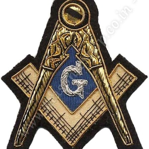 Op de afbeelding: Een geborduurde vrijmetselaarsbadge in goud en zwart met een passer en een winkelhaak, een letter G en een gouden oog.
