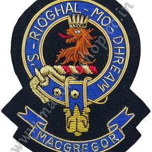 May include: A black embroidered patch with a gold and blue crest featuring a lion, a crown, and the text "S-RIOGHAL-MO-DHREAN-I-MACGREGOR".