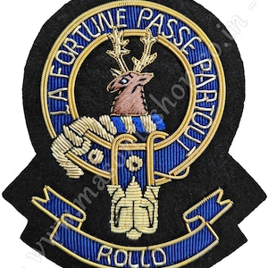 May include: Embroidered patch with a black felt base. The design features a blue and gold circular emblem with the text "LA FORTUNE PASSE PAR TOUT" and a deer. The word "ROLLO" is embroidered on a blue banner.