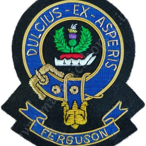 Può includere: Una toppa ricamata su feltro nero, con uno stemma blu e oro. Lo stemma comprende una corda dorata, un cardo dorato e giallo, e uno stendardo dorato con il testo "FERGUSON". Il testo "DULCIUS EX ASPERIS" è ricamato in oro attorno allo stemma.