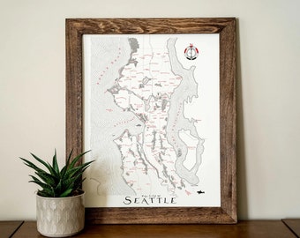 May include: A framed map of the city of Seattle, Washington. The map is in black and white with red lines and text. The map is framed in a dark wood frame.