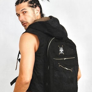 May include: Black backpack with a hood and multiple zippered compartments. The backpack features a white trident logo and the word "WAVERY" printed on the front. The backpack has adjustable straps and a quilted texture.