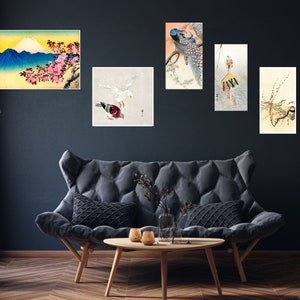 May include: A set of five Japanese-style art prints featuring a mountain scene, a peacock, a bird, a bird with a flower branch, and a bird with a flower branch. The prints are framed and hung on a dark blue wall.