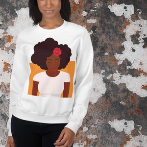 Könnte beinhalten: Weißer Pullover mit einem Grafikdruck einer Frau mit dunkelbraunen Afrohaaren und einer roten Blume im Haar. Die Frau trägt ein weißes T-Shirt und schaut nach unten.