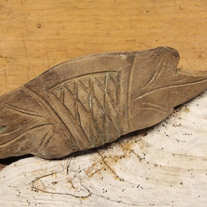 May include: A carved wooden leaf with intricate details, featuring a woven pattern and a raised edge. The leaf is brown and has a natural wood finish.
