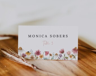 Peut inclure: Carte blanche avec le texte "MONICA SOBERS Table 3" en noir. La carte a une bordure florale avec des fleurs roses, jaunes et violettes.