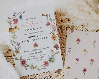 May include: A floral-themed first birthday invitation for a girl named Sophie. The invitation features a watercolor illustration of wildflowers in a wreath with the text "Our Little Wildflower is Turning One!" and details for the party, including the date, time, location, and RSVP information.