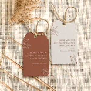 May include: Two gift tags with twine loops. One tag is terracotta, the other is light beige. Both tags have the text "THANK YOU FOR COMING TO CLAIRE'S BRIDAL SHOWER" and "November 27, 2020". Decorative leaf outlines are also present.