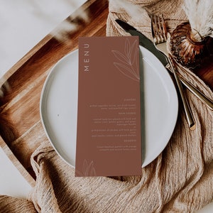 May include: A brown menu card with white text and a simple line drawing of a leaf. The menu lists starters, main course, and desserts. The text reads: "MENU", "STARTERS", "Grilled vegetable terrine, sun dried tomato pesto, and poached tiger prawns", "MAIN COURSE", "Roasted lamb loin glazed with herb and walnut crust, potato gratin, and green asparagus bundle", "Grilled breast of chicken with herb garlic, pearl barley risotto, and glazed shallots", "DESSERTS", "Frozen hazelnut parfait with orange compote and acacia honey sauce"