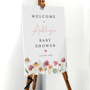May include: Welcome to Ashley's Baby Shower sign with a floral border and the date June 27th, 2022.