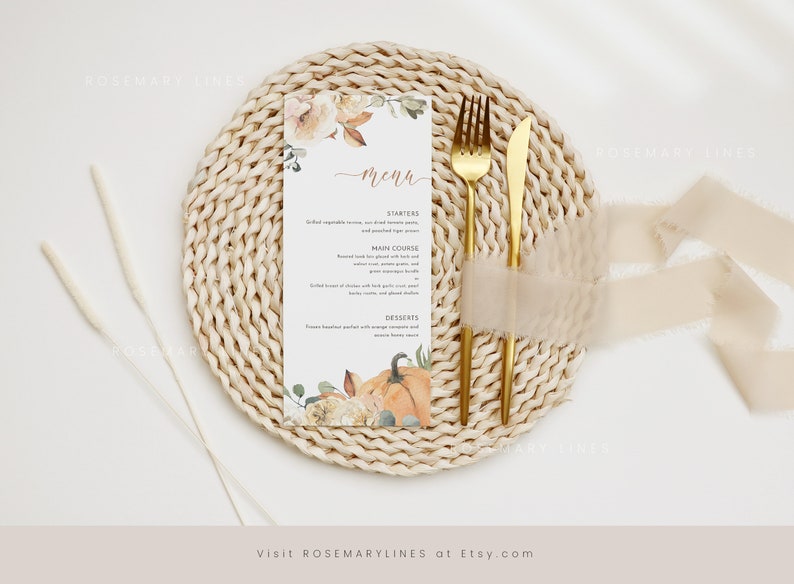 K&ouml;nnte beinhalten: Eine Men&uuml;karte mit floralen und K&uuml;rbis-Illustrationen, goldenem Besteck und einem beigen Band auf einem gewebten Platzset. Das Men&uuml; umfasst Vorspeisen, Hauptgericht und Desserts.