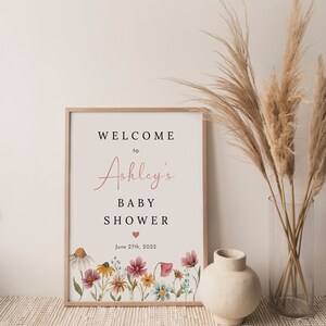 May include: A printable sign for a baby shower with a floral design and the text "Welcome to Ashley's Baby Shower June 27th, 2022".
