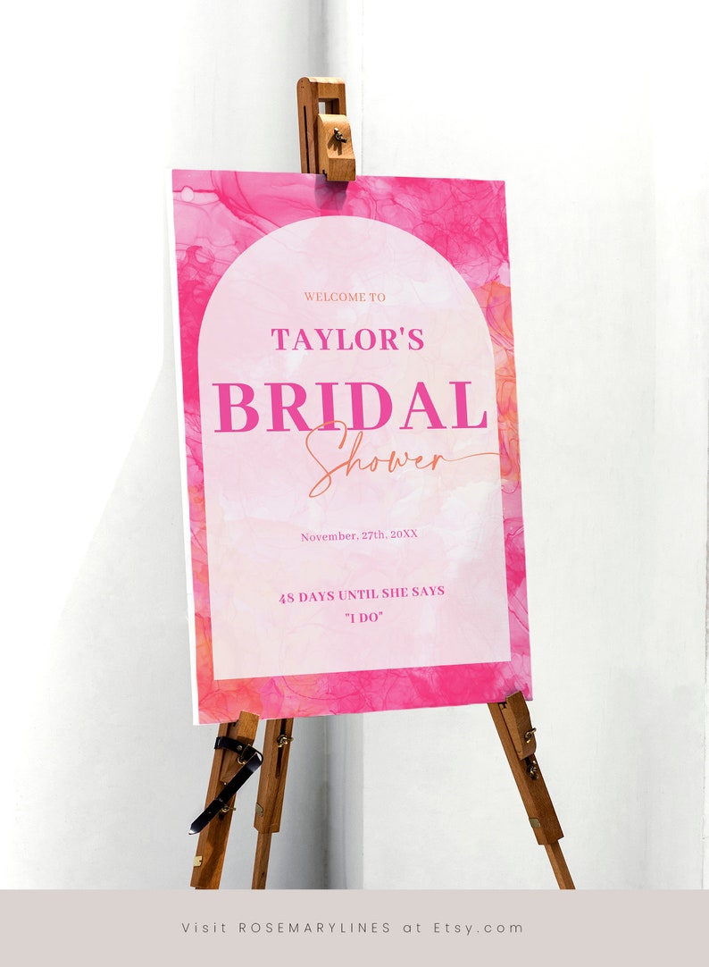 May include: A pink and white bridal shower sign on a wooden easel. The sign reads "Welcome to Taylor's Bridal Shower" with the date and "48 days until she says I do."