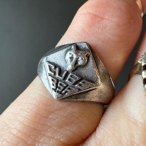 May include: A silver ring with a geometric design featuring a wolf head and the text "CUBS 85".