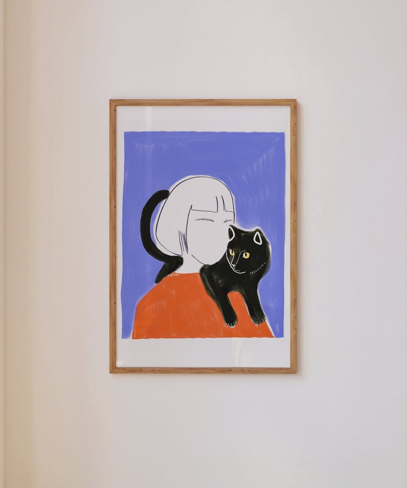 May include: Framed art print featuring a stylized illustration of a person with short white hair and an orange top, holding a black cat with yellow eyes. The background is a solid blue color.