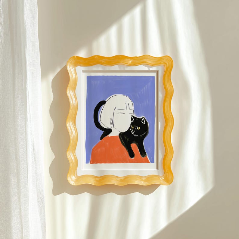 May include: A framed art print featuring a person with a black cat. The artwork has a blue background and an orange shirt. The frame is a wavy, translucent yellow. The art is mounted on a white wall.