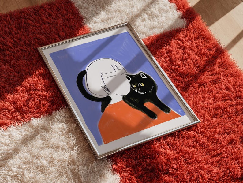 May include: Framed art print featuring a stylized illustration of a person with a black cat. The artwork has a blue background with orange and white accents. The cat is black with yellow eyes. The frame is silver.