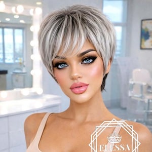 May include: A woman with a short, layered, silver and white wig, wearing a beige tank top. The woman has blue eyes and pink lipstick. The image includes the text "ELESSA" inside a geometric design.