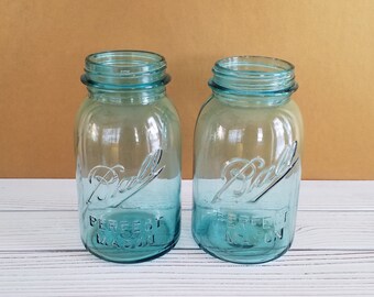 May include: Two vintage blue glass Ball mason jars with the text "Ball Perfect Mason" on the front.
