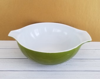 May include: A green and white mixing bowl with a white interior and a green exterior. The bowl has a rounded shape and two handles on the sides.