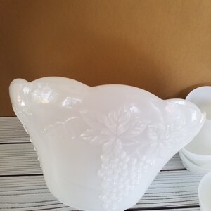 May include: White milk glass punch bowl with a grapevine design. The bowl has a scalloped edge and is in excellent condition.