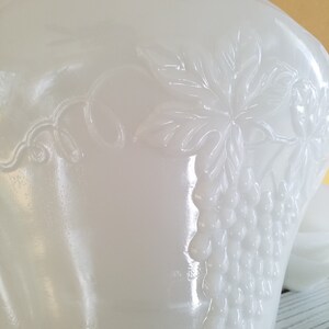 May include: White milk glass bowl with an embossed grapevine design. The bowl has a scalloped edge and is perfect for serving salads, fruit, or desserts.