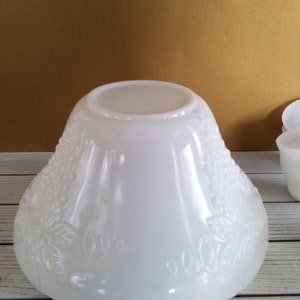 May include: White milk glass punch bowl with a grape design. The bowl is round and has a wide rim. It is made of opaque white glass and has a smooth, glossy finish.