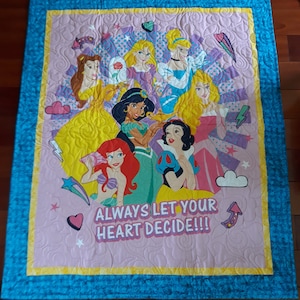 May include: A pink and blue quilted blanket with a colorful image of Disney princesses and the text "Always let your heart decide!!"