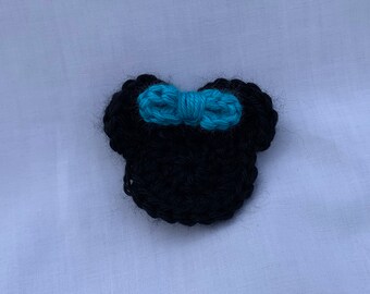 May include: A black crocheted mouse head with a blue bow.