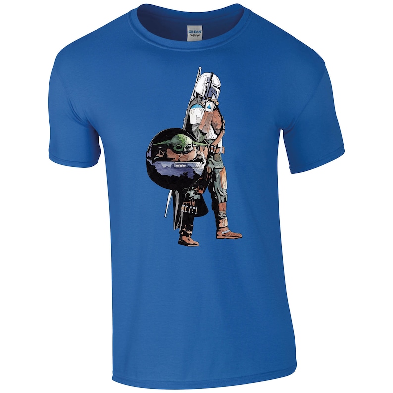 K&ouml;nnte beinhalten: Ein blaues T-Shirt mit einem Grafikdruck eines Mandalorianer-Charakters aus Star Wars, der ein kleines gr&uuml;nes au&szlig;erirdisches Wesen h&auml;lt.