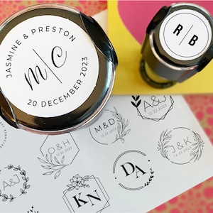 May include: A collection of self-inking wedding stamps with various designs. The stamps feature initials, dates, and floral motifs. One stamp reads "Jasmine & Preston" with the initials "m/c" and the date "20 December 2023".