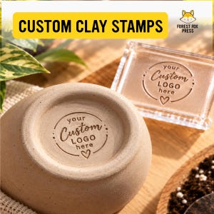 May include: A clear acrylic stamp with the text "your Custom LOGO here" and a heart icon, positioned next to a beige clay bowl featuring the same stamped impression. The image includes the text "CUSTOM CLAY STAMPS" and "FOREST FOX PRESS".