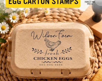 May include: A tan moulded pulp egg carton stamped with black ink. The design features a chicken illustration, the text Wilson Farm, fresh CHICKEN EGGS, and the phone number 865-888-8088, accented by decorative leaf and heart motifs.