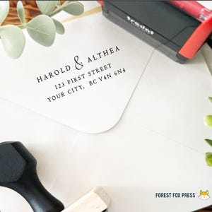 May include: A white envelope with the names "HAROLD & ALTHEA" and address details printed in black. A black and red stamp is visible, along with a wooden stamp. The words "FOREST FOX PRESS" are also printed on the envelope.