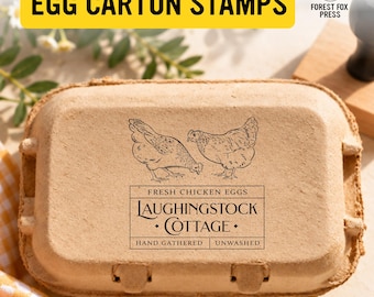 May include: A tan cardboard egg carton featuring a black ink stamp of two chickens and the text: FRESH CHICKEN EGGS, LAUGHINGSTOCK COTTAGE, HAND GATHERED, UNWASHED. The carton has a rectangular shape with a hinged lid and molded closure tabs.